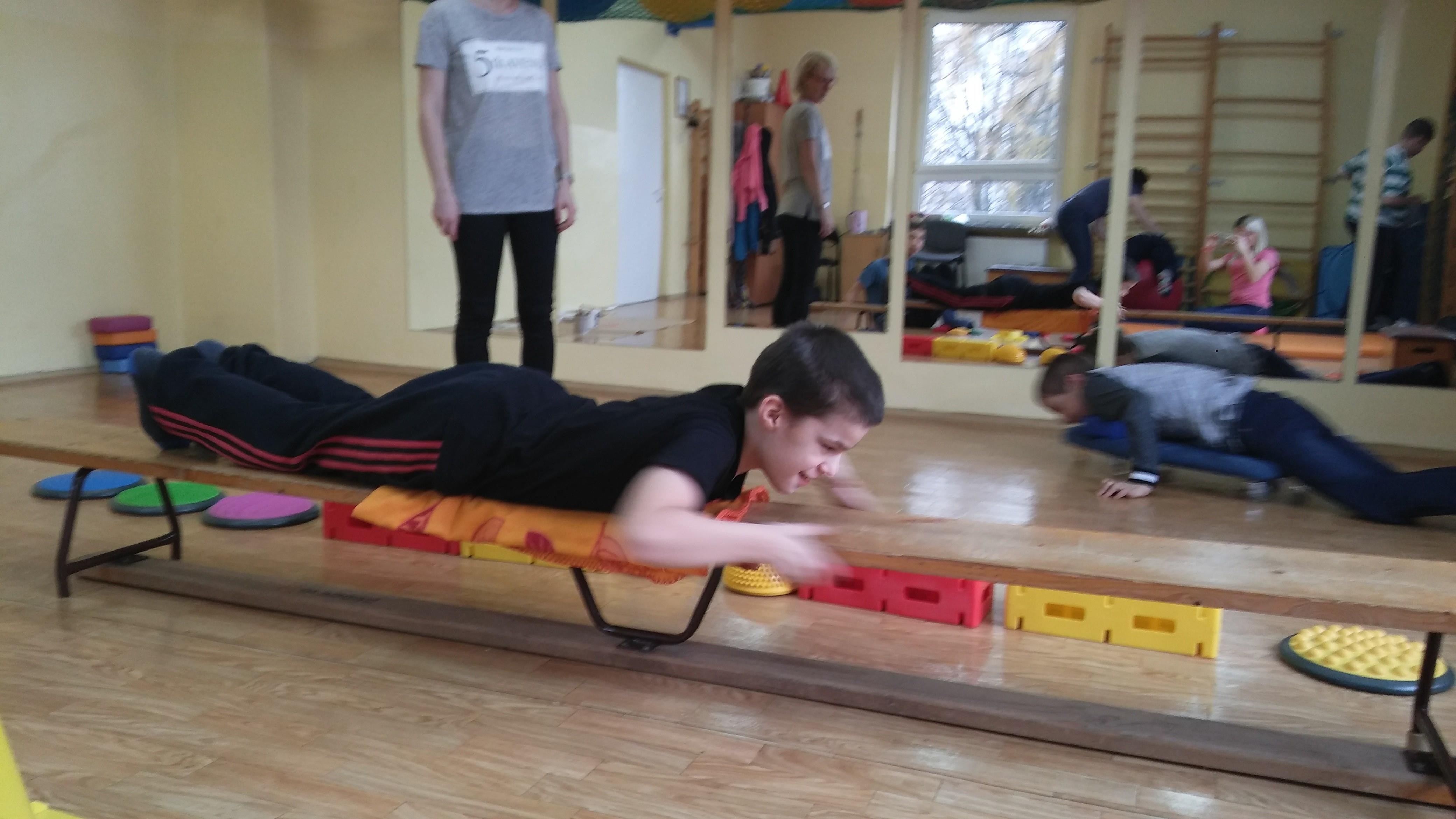 zdjęcie przedstawia ucznia wykonującego ćwiczenie na ławeczce podczas zajęć korekcji wad postawy