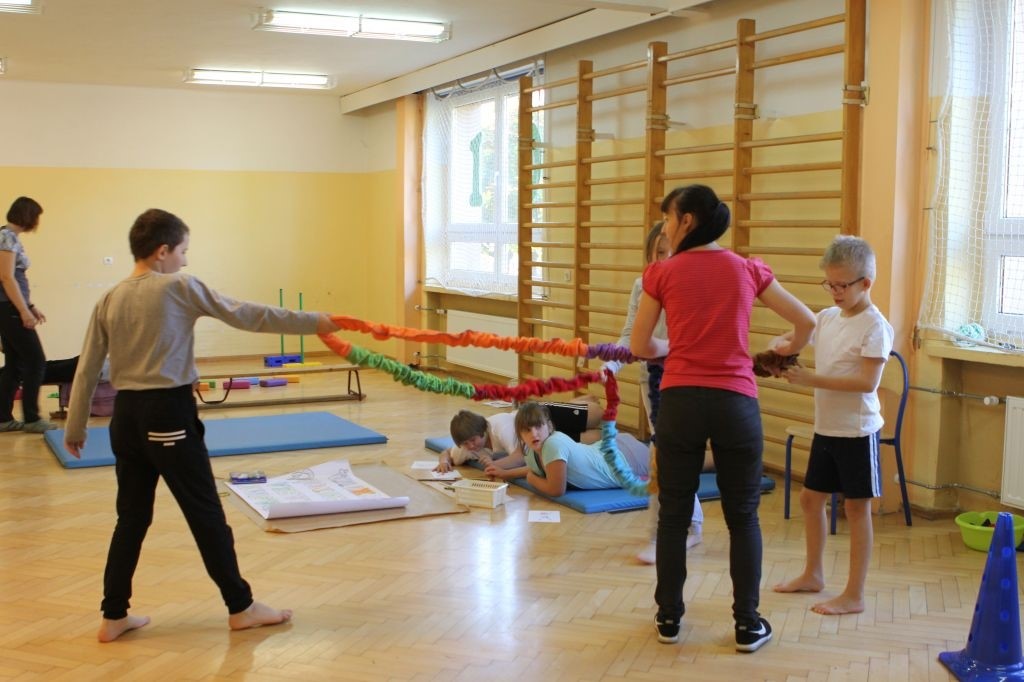 zdjęcie przedstawia uczniów i nauczyciela podczas zajęć rozwijacych koordynację ruchową