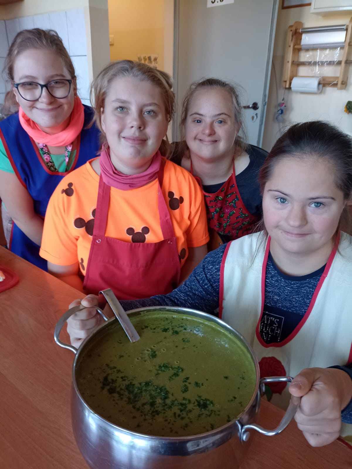 uczennice z garnkiem zielonej zupy krem